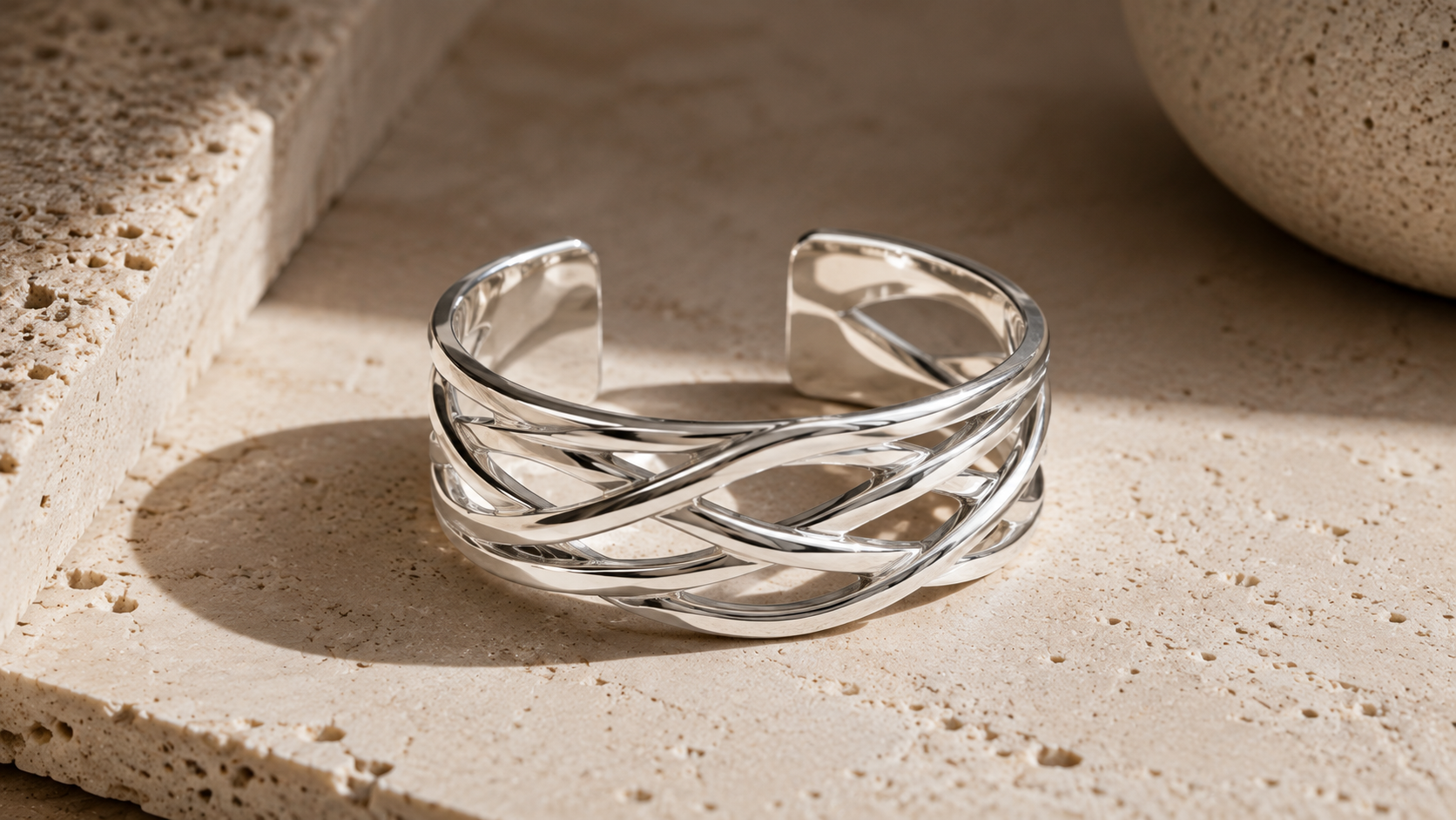 Woven sterling silver cuff photographed on a travertine surface