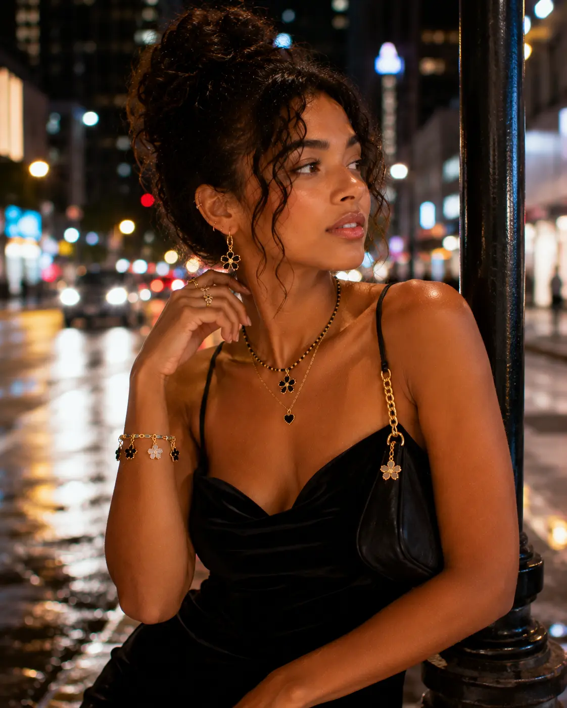 Woman in a black bustier top with a gold chain bag on a city street at night