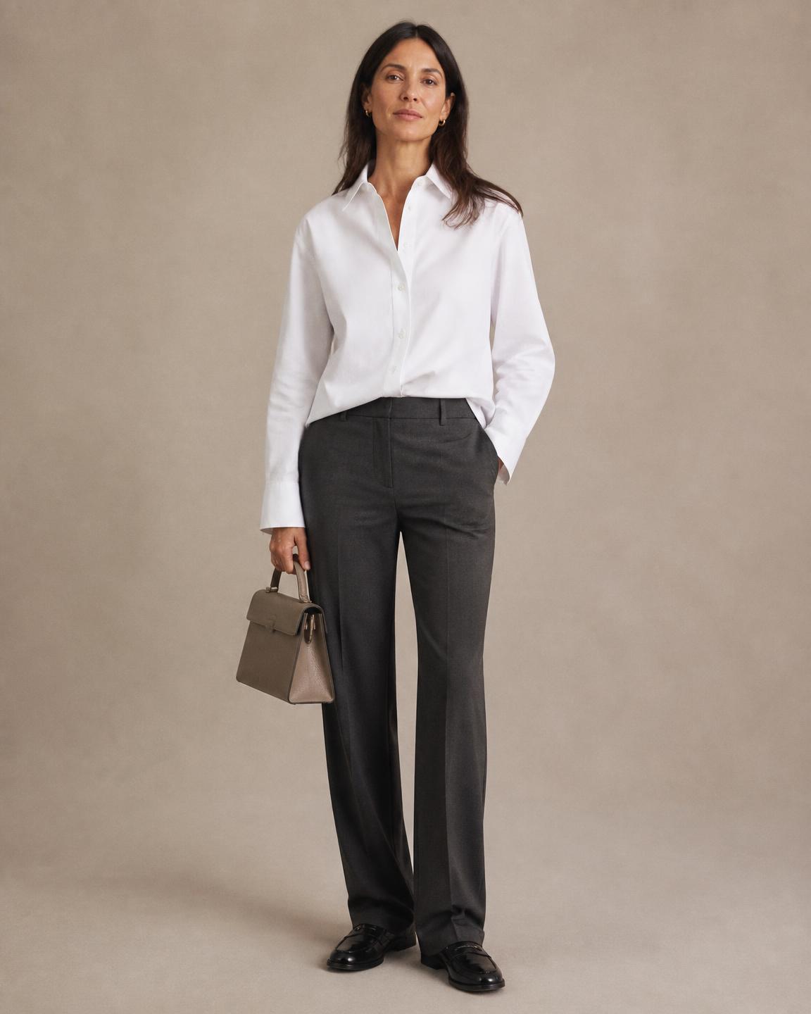 Woman wearing a white shirt, charcoal trousers, and black loafers